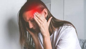 Young woman touching her temples and suffering from head pain, headache or migraine