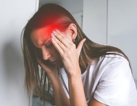 Young woman touching her temples and suffering from head pain, headache or migraine